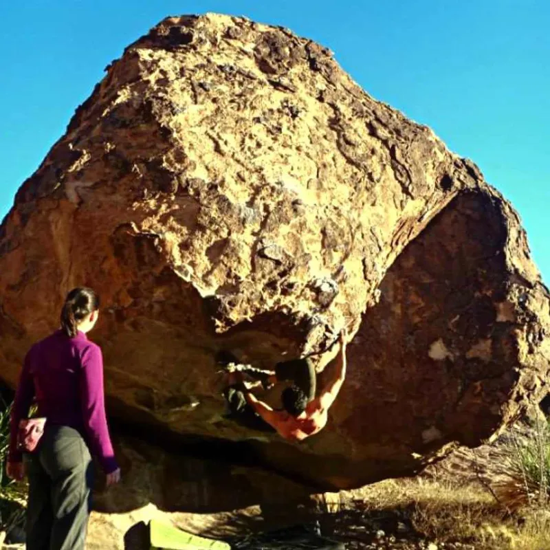 hombre escalando un boulder en posicion incomoda