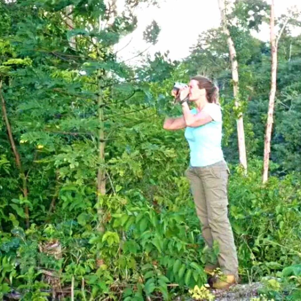 mujer con binoculares del tour senderismo en selva maya chetumal